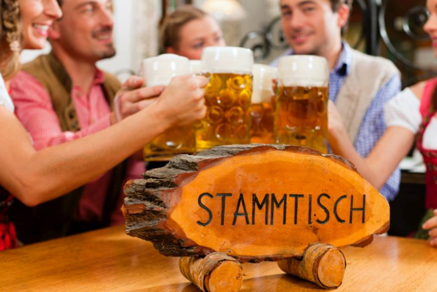 Menschen mit Maßkrügen Bier an einem Stammtisch. (Symbolbild: kzenon)