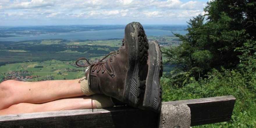 Wanderer rastet auf einer Bank mit Blick auf den Chiemsee (Symbolbild: Marjon Besteman)