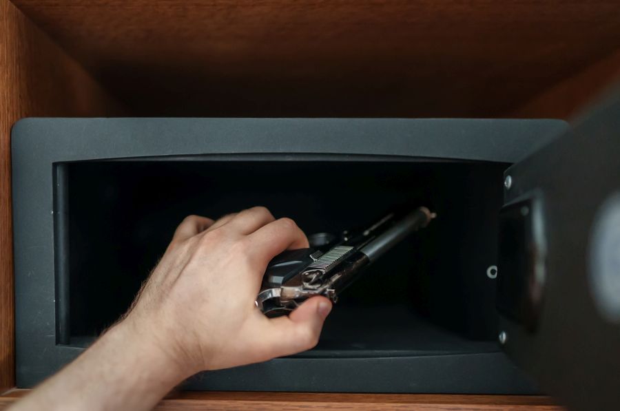 Ein Mann nimmt eine Pistole aus einem kleinen Tresor. (Symbolbild: istock/M-Production)