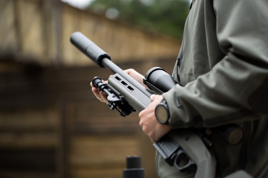Ein Mann hält ein Gewehr mit Schalldämpfer und Zielfernrohr in den Händen. (Symbolbild: iStock/Artem Zakharov)